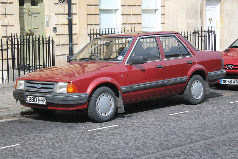  :: „1985 Ford Orion 1.6 Ghia (9703742418)“ von Charlie from United Kingdom - 1985 Ford Orion 1.6 Ghia. Lizenziert unter CC BY 2.0 über Wikimedia Commons - https://commons.wikimedia.org/wiki/File:1985_Ford_Orion_1.6_Ghia_(9703742418).jpg#/media/File:1985_Ford_Orion_1.6_Ghia_(9703742418).jpg